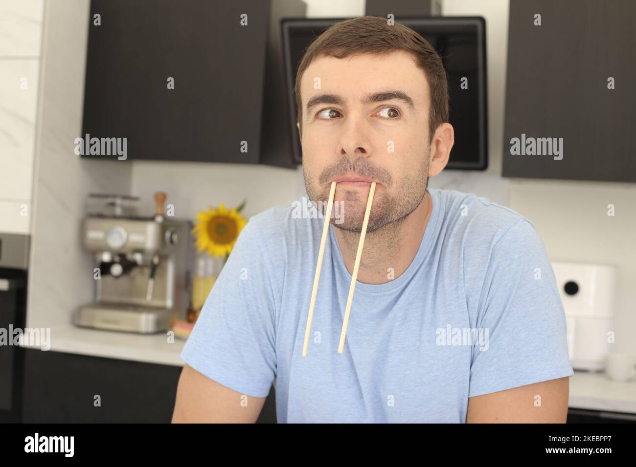 Man making funny face with pair of chopsticks Stock Photo