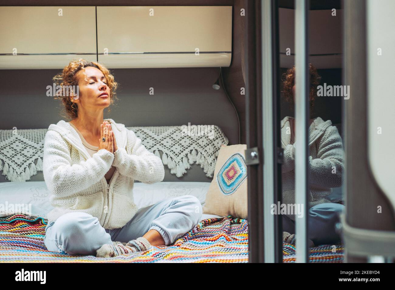 One woman doing meditation and praying leisure activity alone in camper van bedroom. Concept of people and alternative zen lifestyle. Travel on transport caravan vehicle concept life. Healthy mind Stock Photo