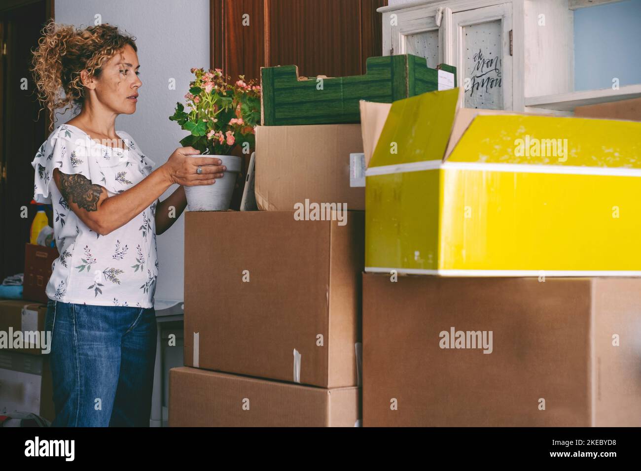 Woman preparing to move in a new house. Adult female enjoy unpacking her stuffs at home. Mortgage and apartment renting concept. People moving and loan. Caucasian middle age lady working indoor Stock Photo