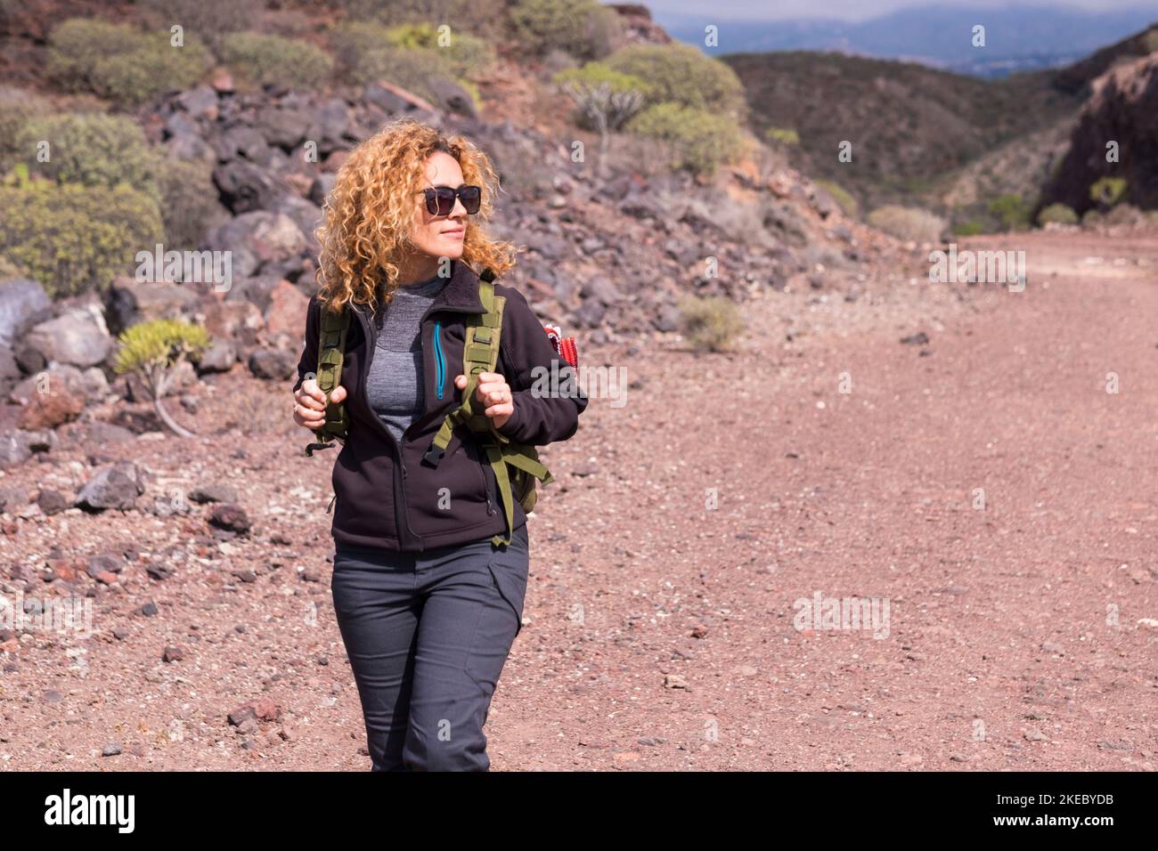 One woman in outdoor leisure activity walking in trekking hiking trip. Travel female people enjoying nature and park outdoors. Sporty lady explore mountains with a backpack Stock Photo