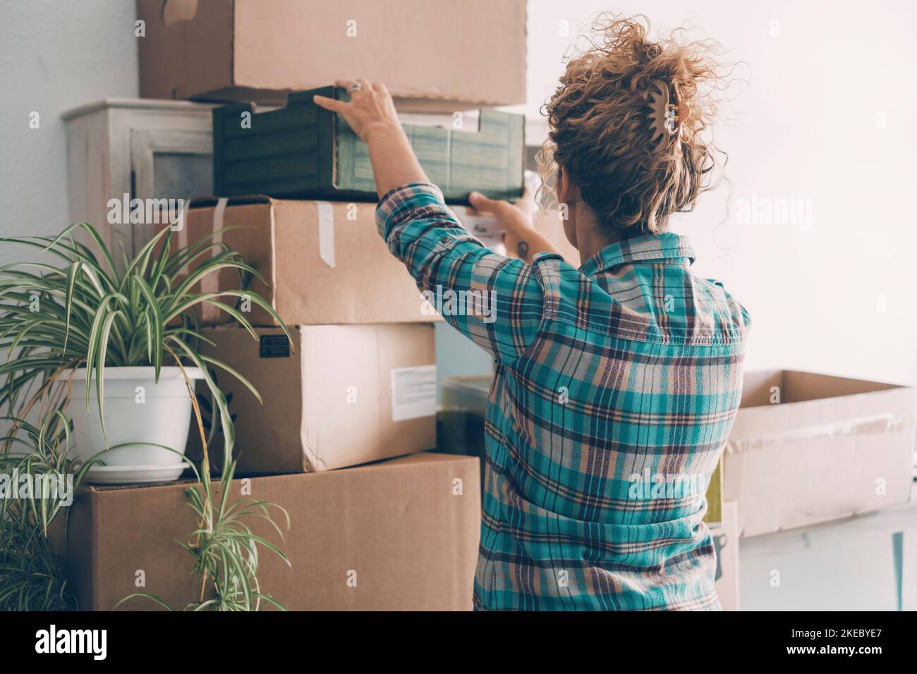 Back view of young woman unpacking after moving to a new home.. Concept of cardboards boxes and work to move and change house. New life concept. Loan and mortgage economy. Independence lady leisure Stock Photo