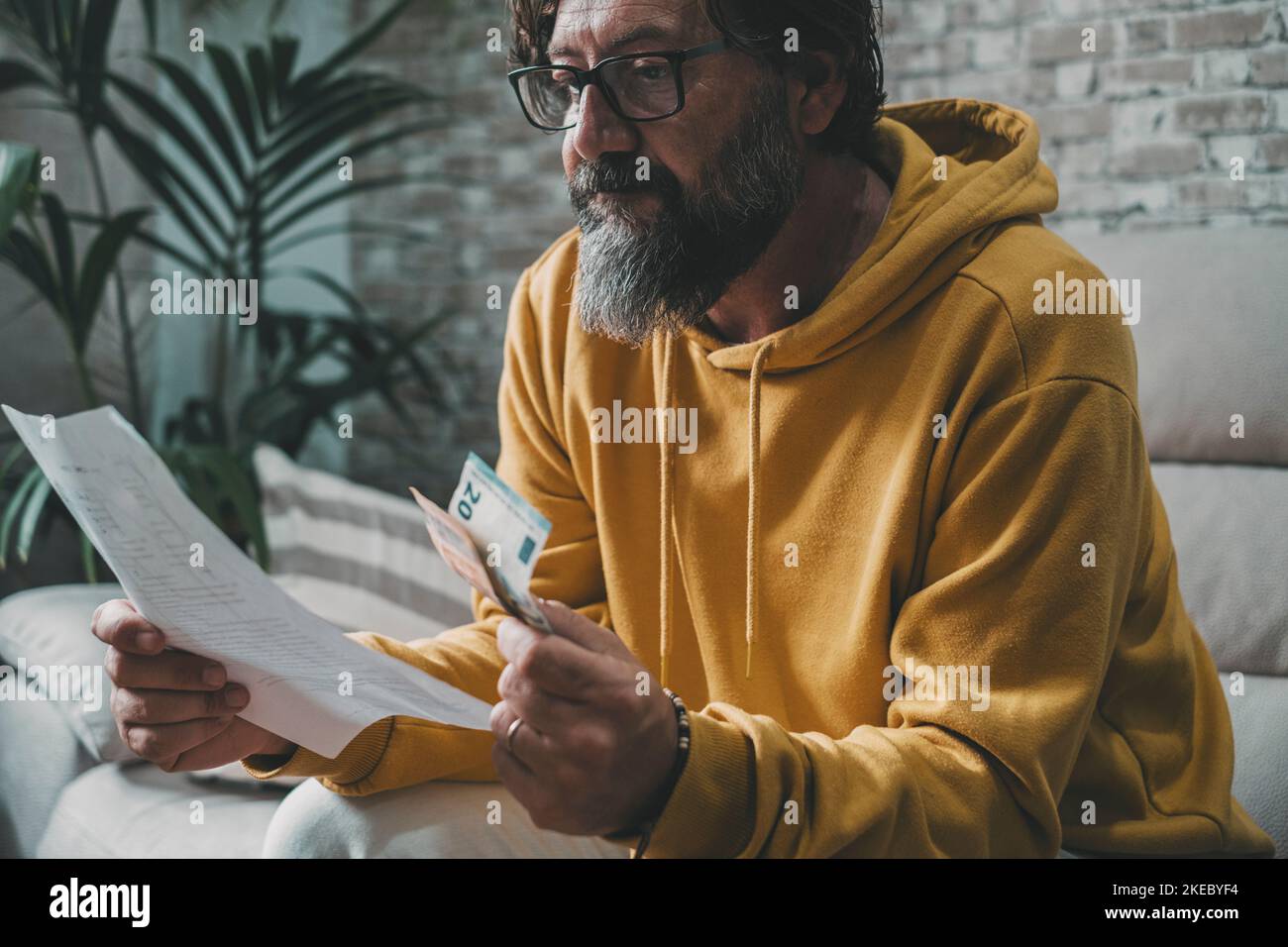 Man with economy problems looking bills and costs document and taking last banknotes on hand. Worried expression portrait. People looking for business job solution. Family and crisis concept life Stock Photo