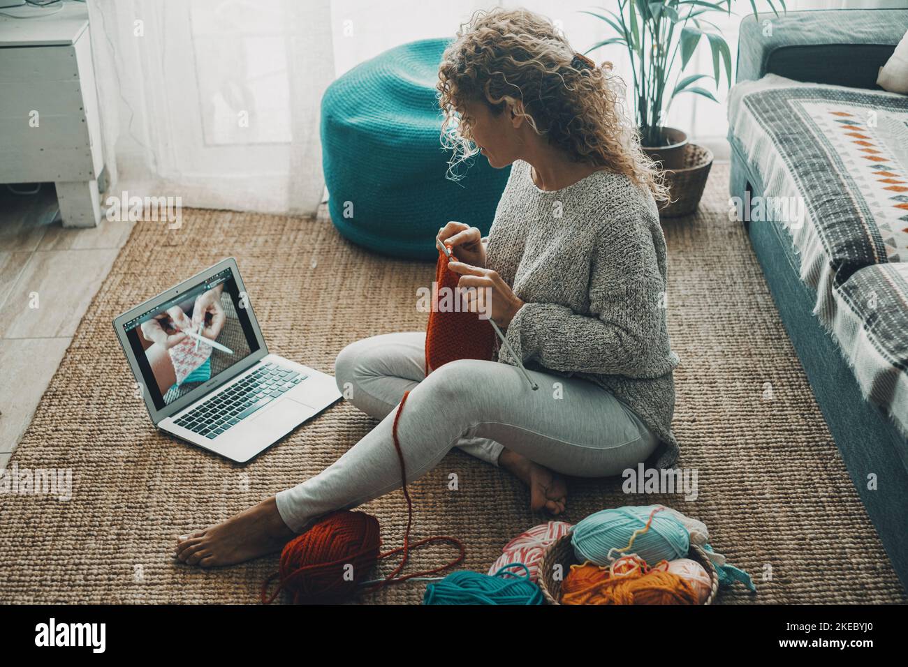 Woman at home doing knit work for hobby and leisure activity alone watching tutorial on line on internet channel. Concept of people and diy work indoor. People and online content creator job ideas Stock Photo