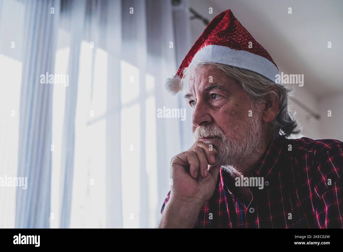 one alone and sad senior mature man sitting on the sofa at home celebrating christmas day alone with anyone people - upset adult feeling wrong Stock Photo