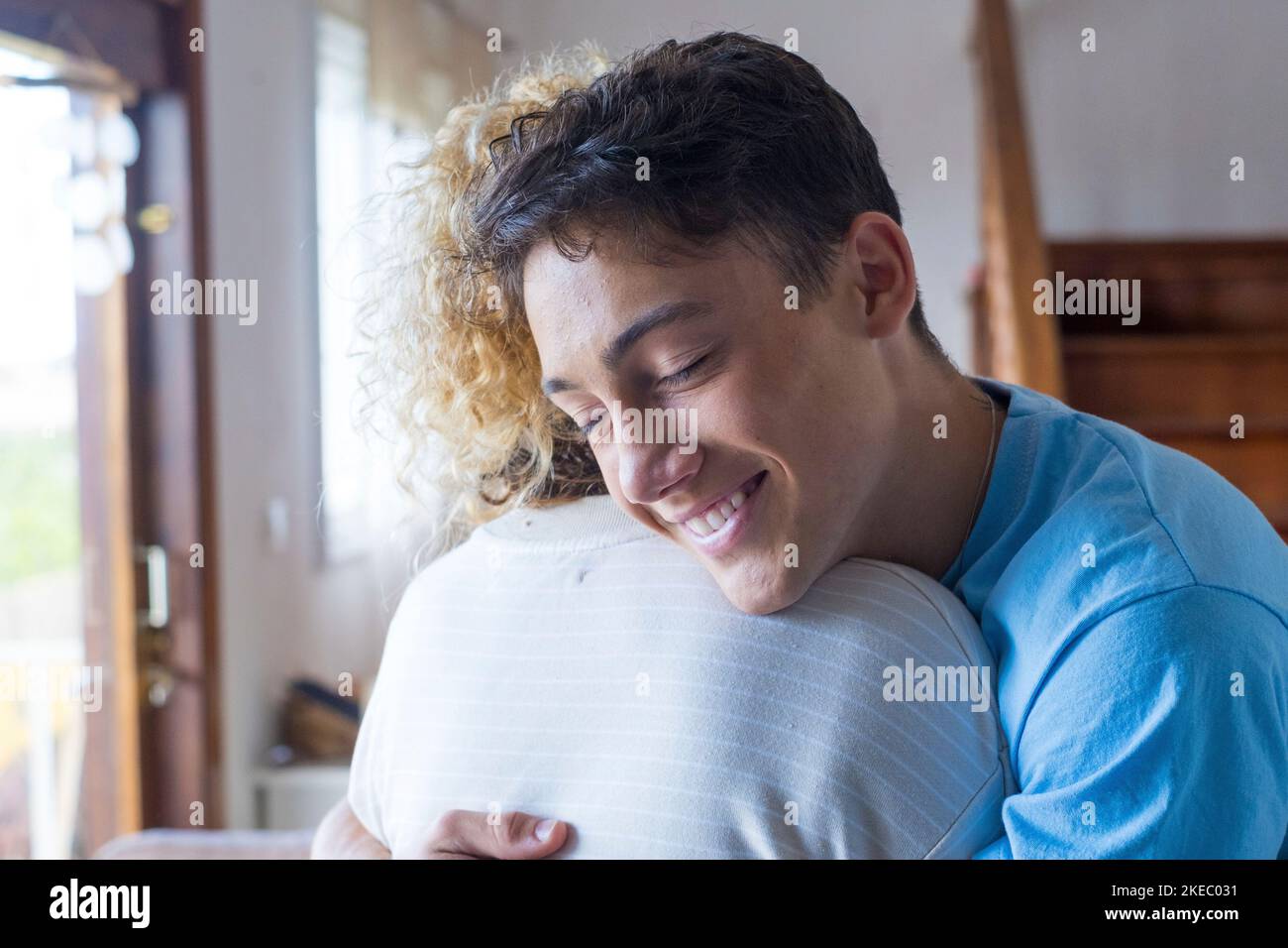 Loving teenager smiling enjoy moment strong cuddles adult mom after long separation, mother glad to see son multi generational family reunion, love and bonding concept Stock Photo
