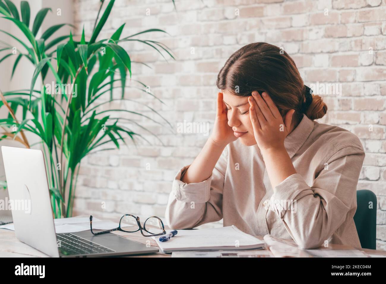 Tired bored teenage girl school student feeling headache or fatigue doing homework at home. Exhausted depressed sick teenager studying alone worried about difficult education problems concept. Stock Photo