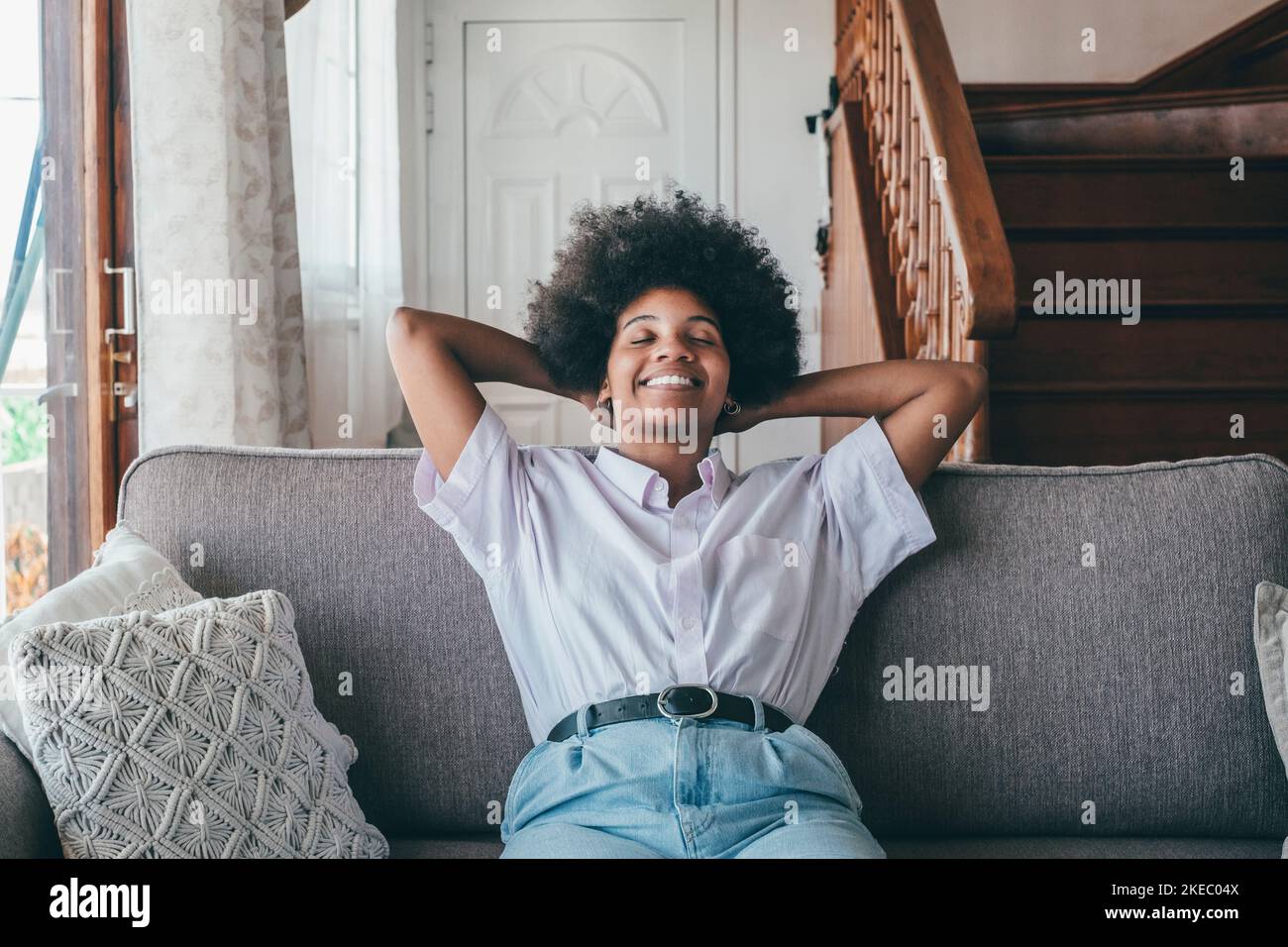 Happy african american woman sitting on sofa with eyes closed and ...