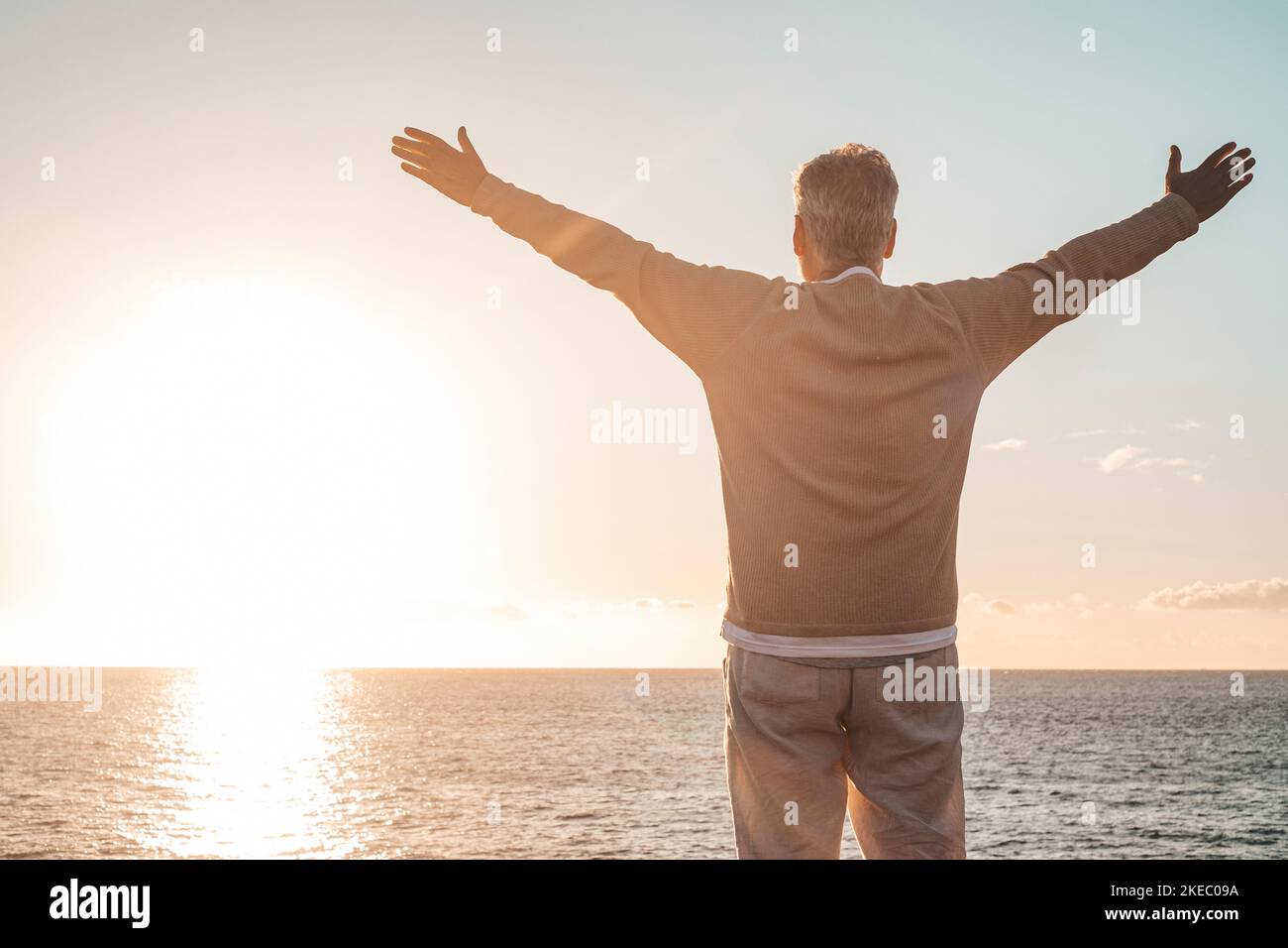 old man looking to the sunset and the sea with opened arms feeling free and happy - freedom and happiness feel lifestyle and concept Stock Photo