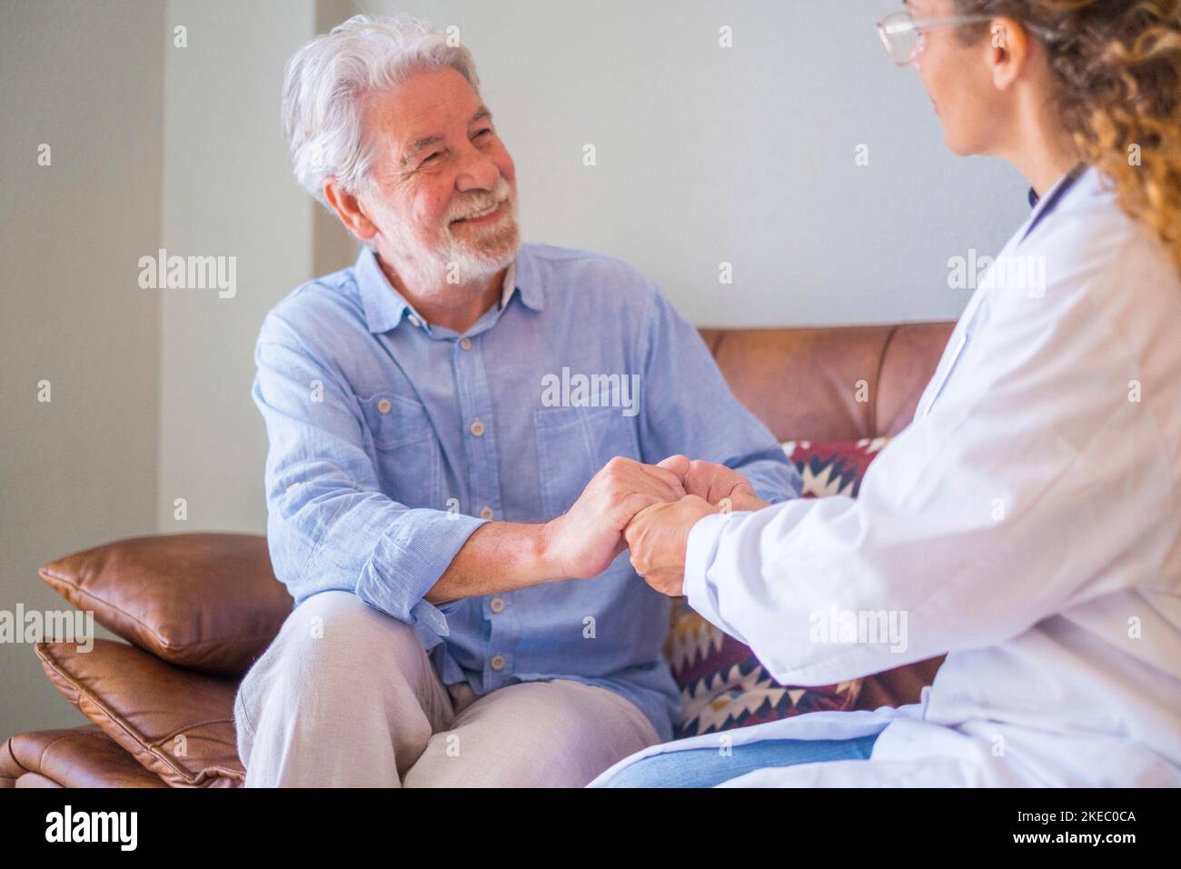 Young female doctor checking and helping senior man at his home. Doctor