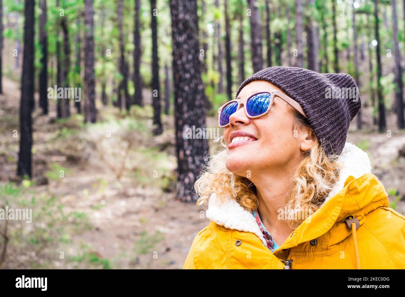 portrait of beautiful woman looking and enjoying nature in a forest with some trees - traveling and vacations in mountain Stock Photo