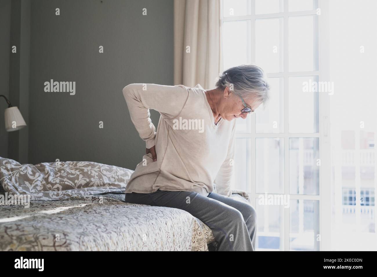 Tired senior woman suffering from backache after sleep, rubbing stiff muscles, Old female