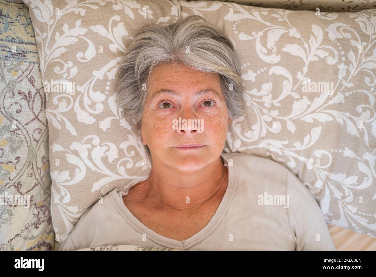Senior insomaniac woman lying awake in bed looking up and trying to