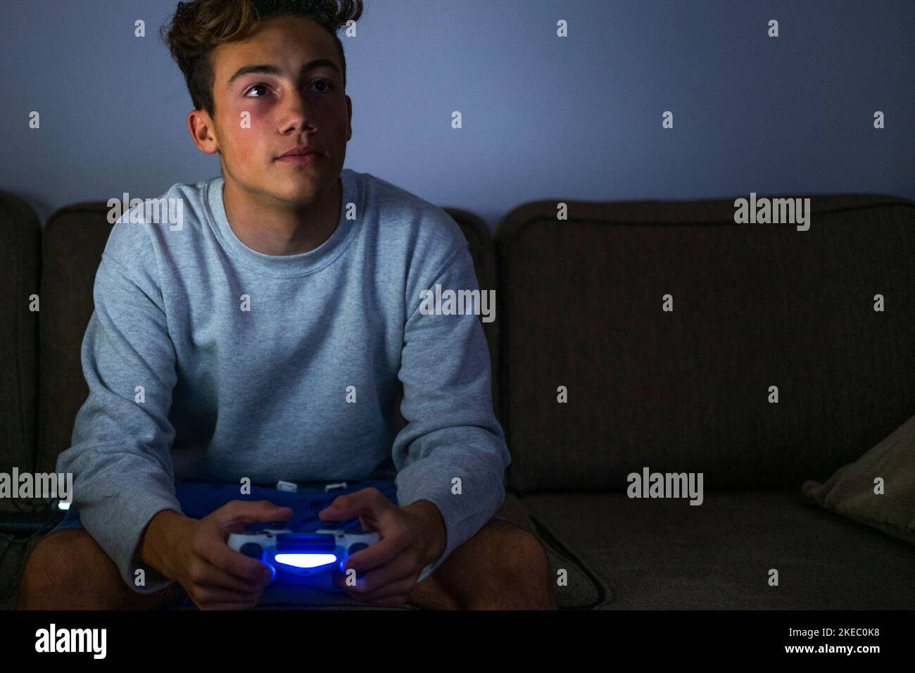 portrait and close up of teenager or millenial playing video games with a controller at home in late night on the sofa - bad unhealthy lifestyle of most part of boys Stock Photo