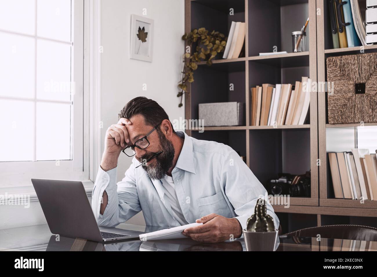 Unhealthy old stressed businessman looking at laptop, using computer