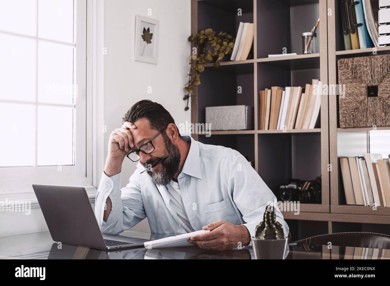 Unhealthy old stressed businessman looking at laptop, using computer, suffering from work too much or long computer overwork. Stock Photo
