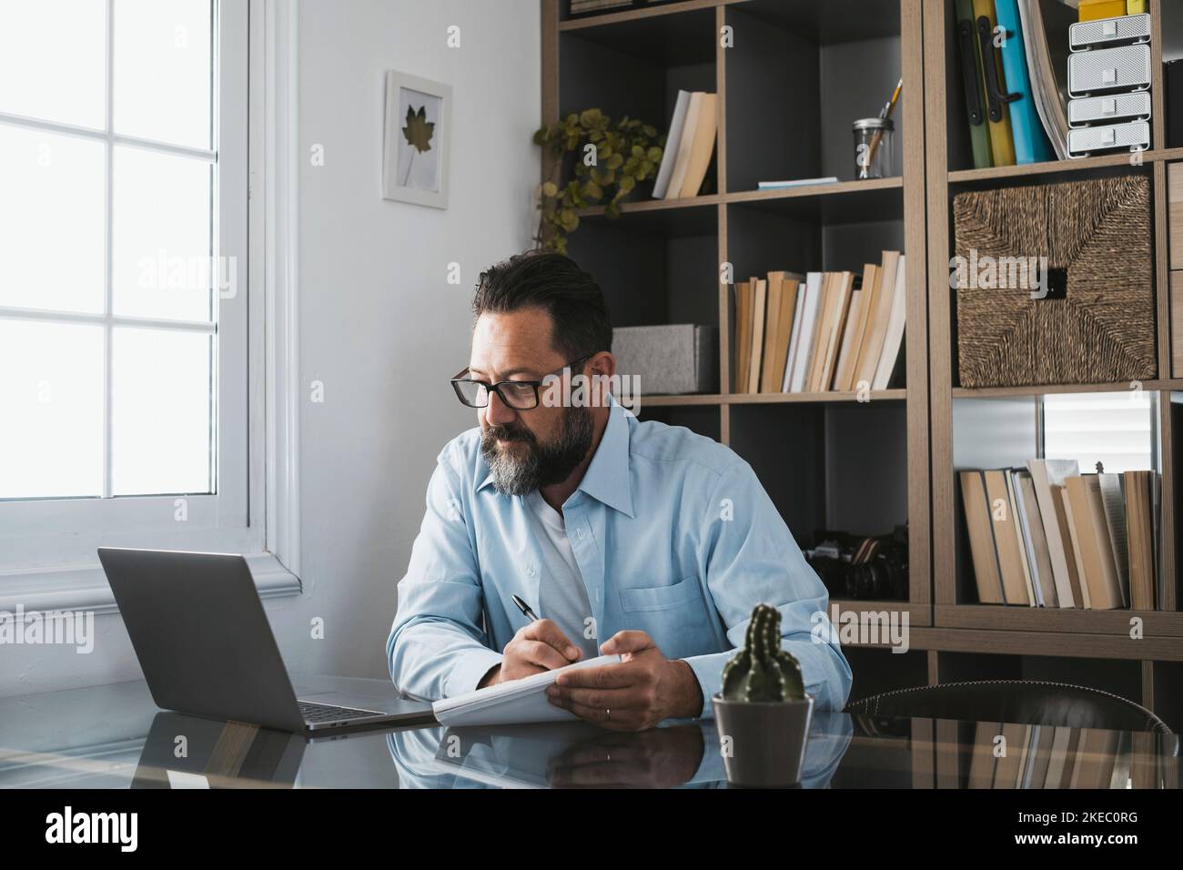 Happy young caucasian businessman smiling working online watching webinar podcast on laptop and learning education course conference calling make notes sit at work desk, elearning concept Stock Photo