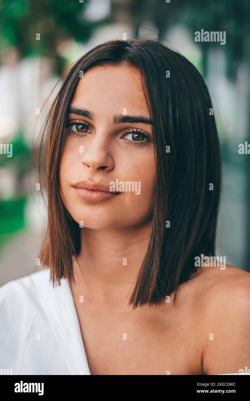 Happy young fashionable woman with short hair looking at camera outdoors. Beautiful satisfied lady with short hair smiling while facing camera. Portrait of confident female youth smiling Stock Photo