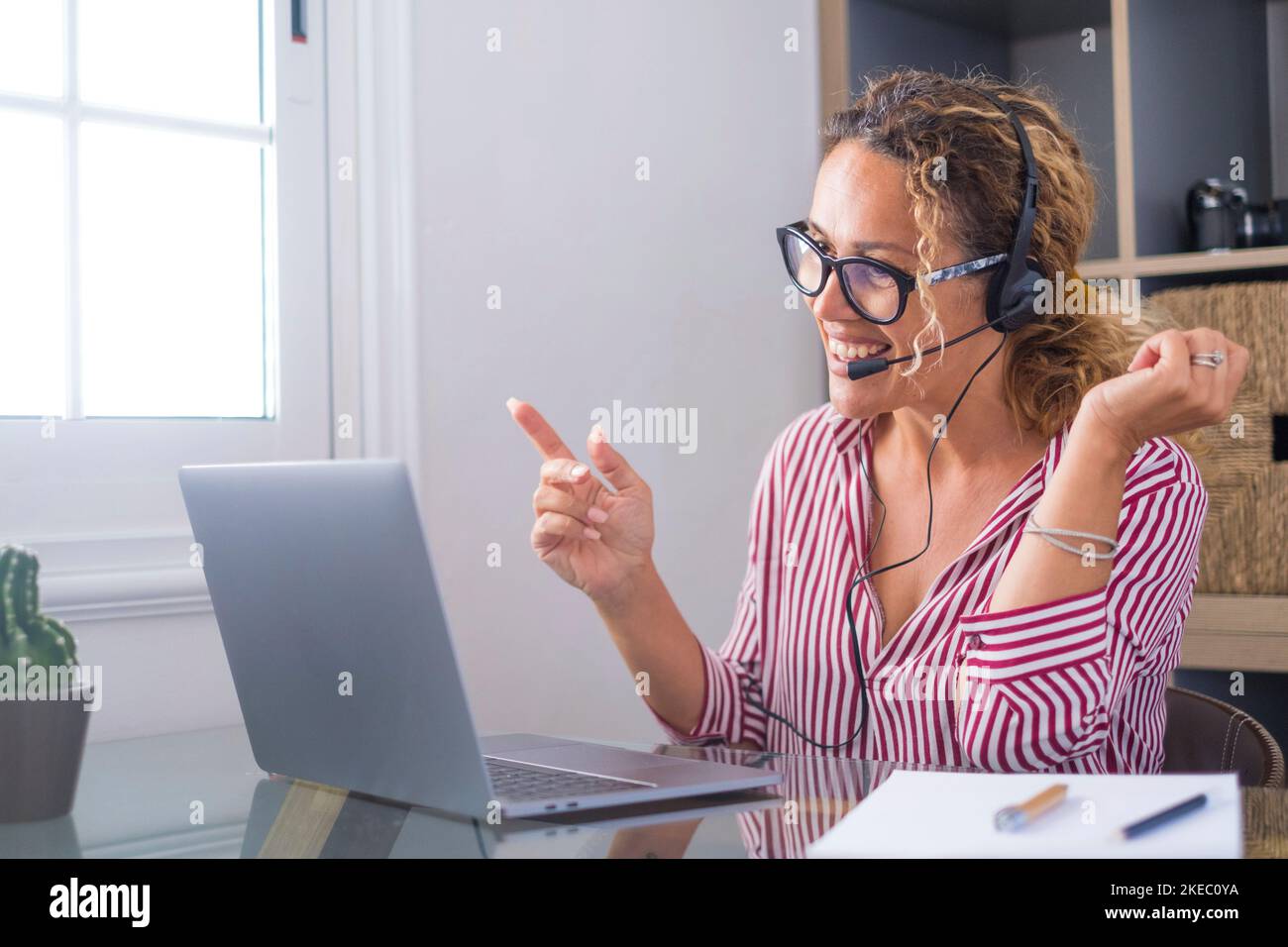 Attractive caucasian woman sit at homeoffice room wearing headset take part in educational webinar using laptop. Video call event with clients or personal chat with friend remotely concept Stock Photo