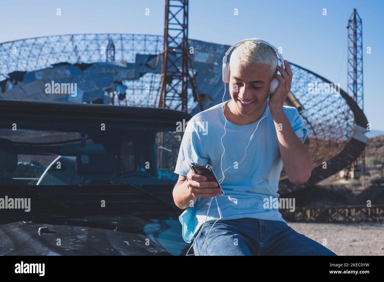 one teenager or caucasian man using his phone and device alone on his car vehicle - technology addicted concept and online lifestyle - traveler in vacations looking at the maps his tablet Stock Photo