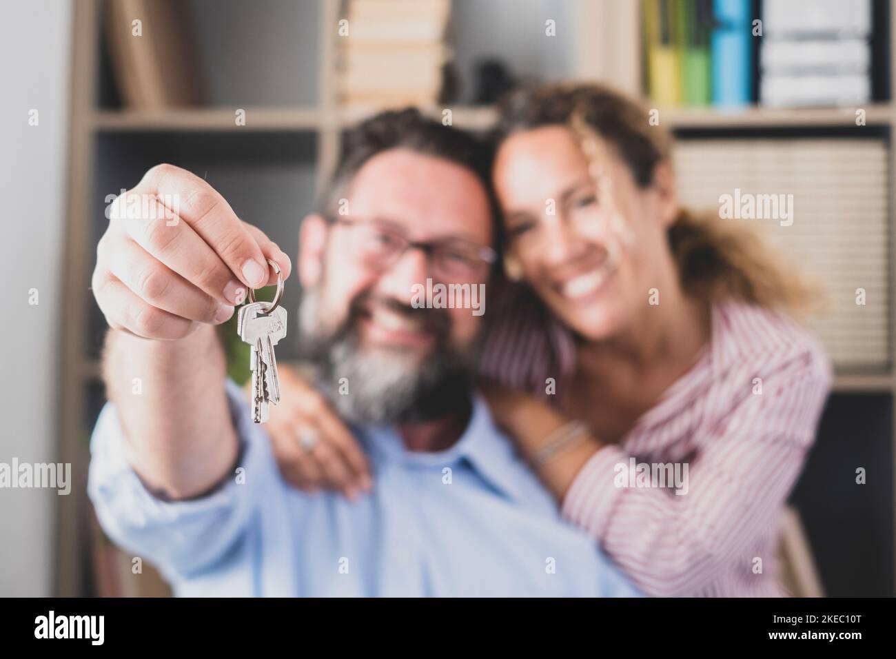 Happy couple showing keys of their new house or office. Portrait of smiling wife with husband holding key to their new apartment. Two tenant or renter moving or relocating with keys in hand Stock Photo