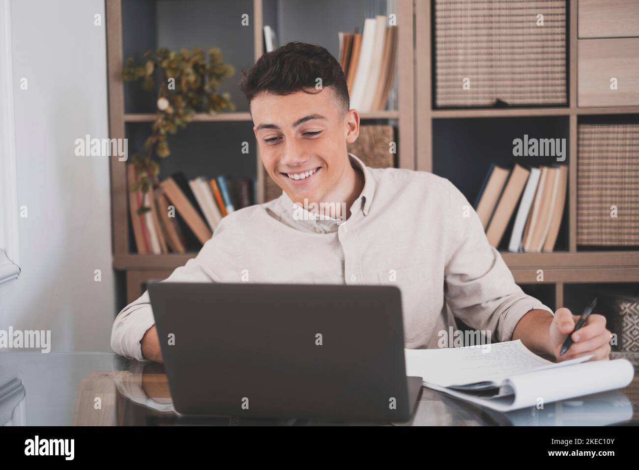 Happy young caucasian businessman smiling working online watching webinar podcast on laptop and learning education course conference calling make notes sit at work desk, elearning concept Stock Photo