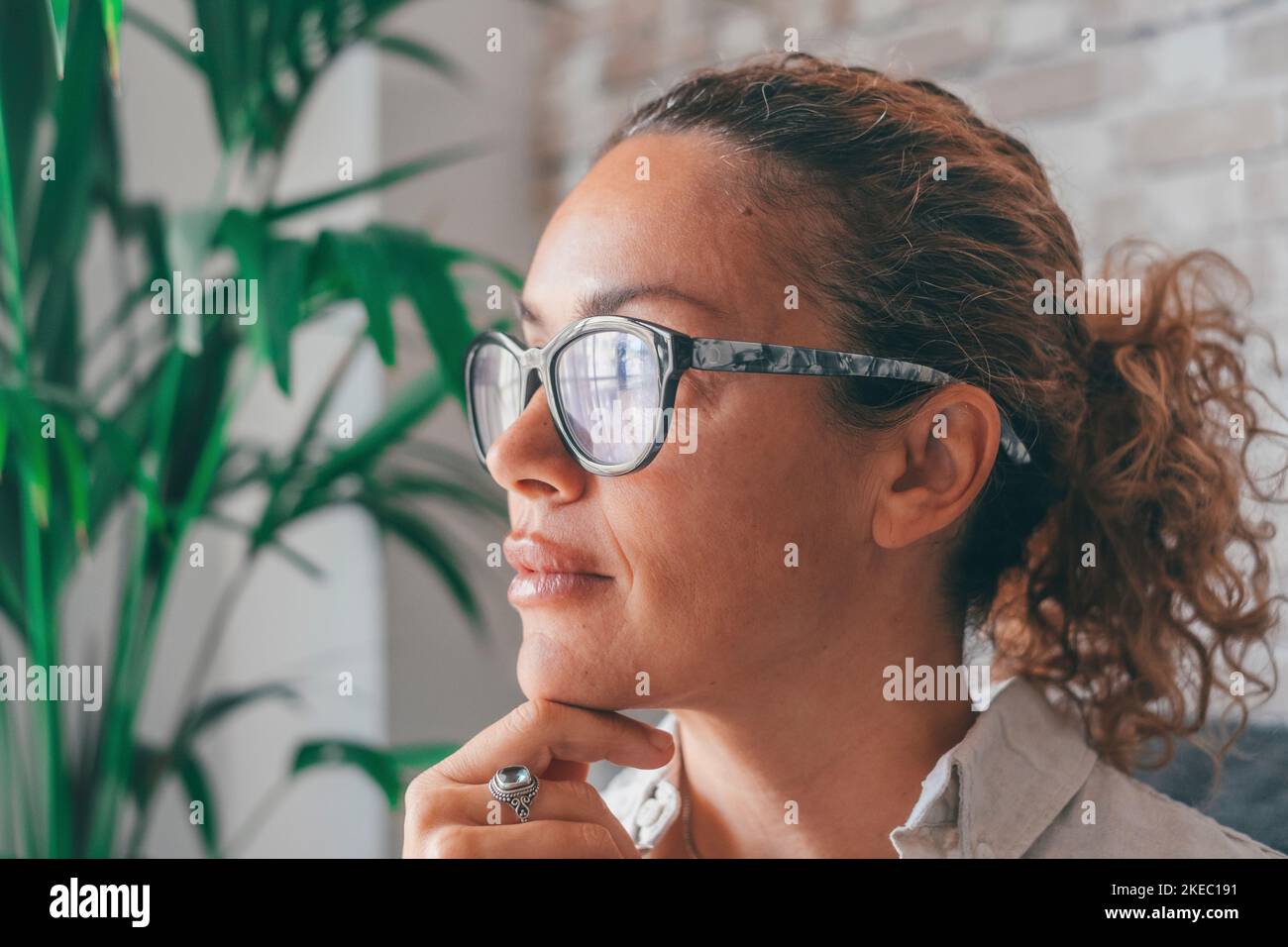 Happy thoughtful millennial business woman in casual looking at window with pensive dreamy smile, thinking of work project future vision, ambitious career, planning goals. Head shot portrait Stock Photo