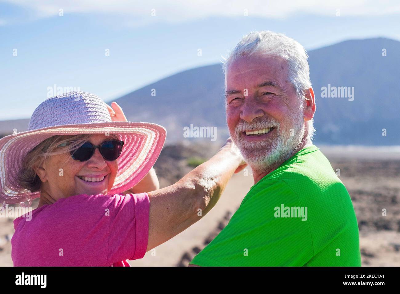 couple of seniors in a holiday together having fun - two mature people looking at the camera smiling and laughing - woman inndicating something with her arm Stock Photo
