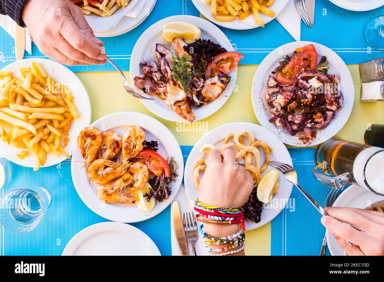 group of people eating and drinking together - eat fish and healthy food - table with plate with food Stock Photo