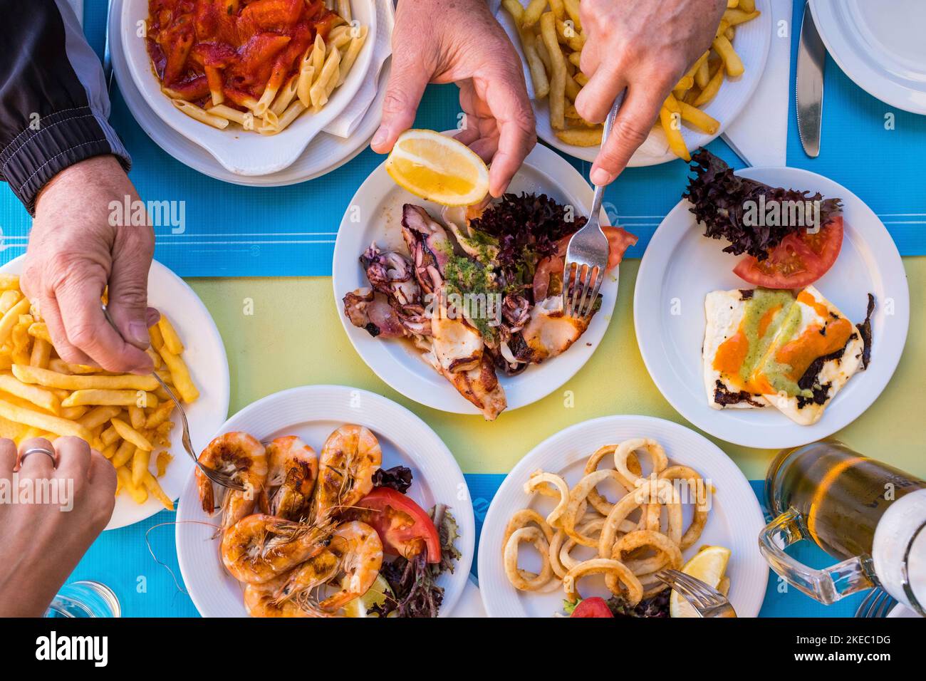 beautiful close up of table woth gourmet and marine food like fish and chips with hands taking it - group of people eating together - above and top view Stock Photo