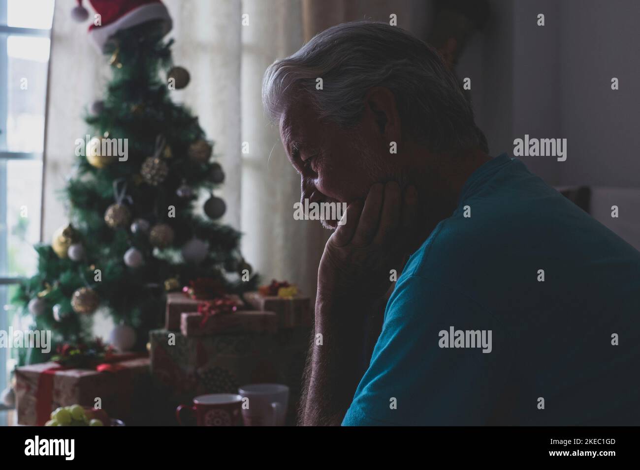 one alone and sad senior mature man sitting on the sofa at home at christmas time Stock Photo