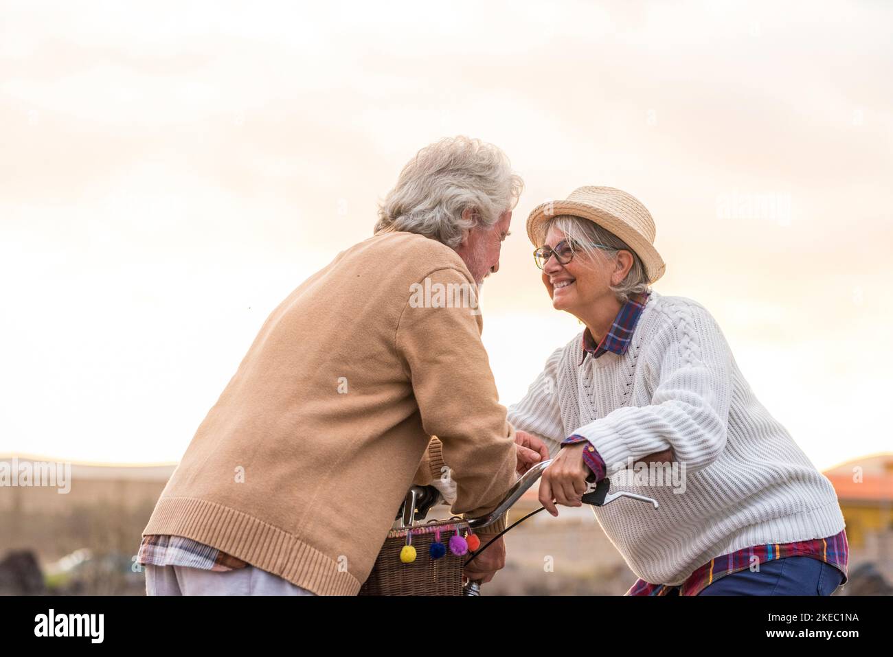 two seniors together smiling and enjoying looking each other - mature woman with a bike looking at the pensioner man with love Stock Photo