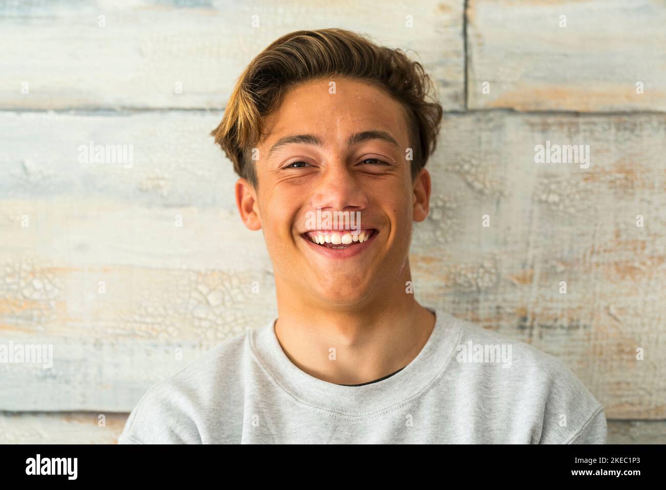 close up of beautiful teenager smiling and laughing alone at home - portrait of face of young man Stock Photo