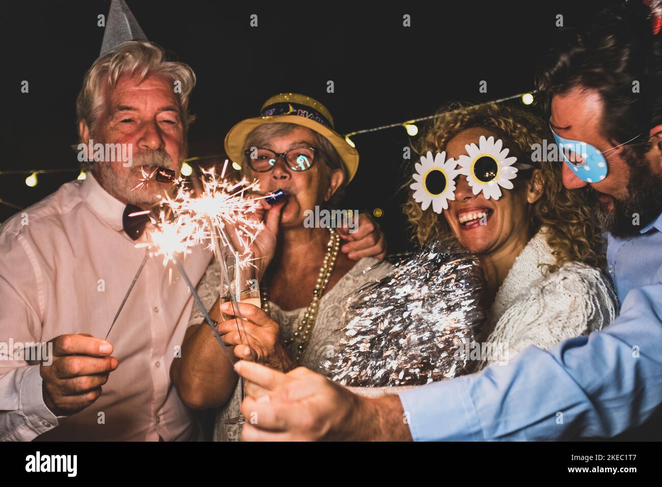 group of people having fun and enjoying new year night together celebrating with sparklers and funny accessories - happy lifestyle Stock Photo