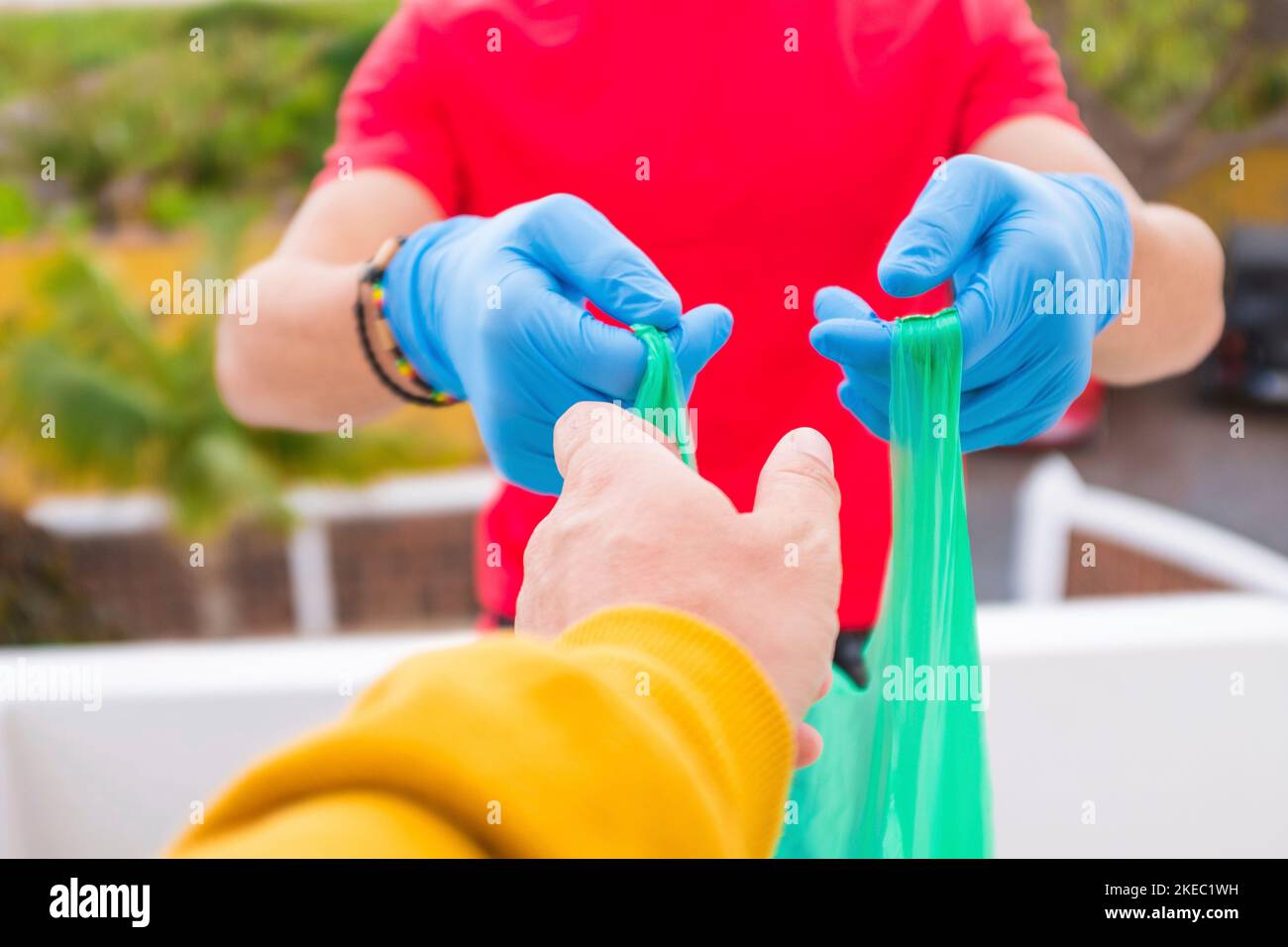 close up of hands of needing poor people taking a bag with food and water to be healthy in the quarantine lockdown - vouluntaire man giving things to people at home Stock Photo