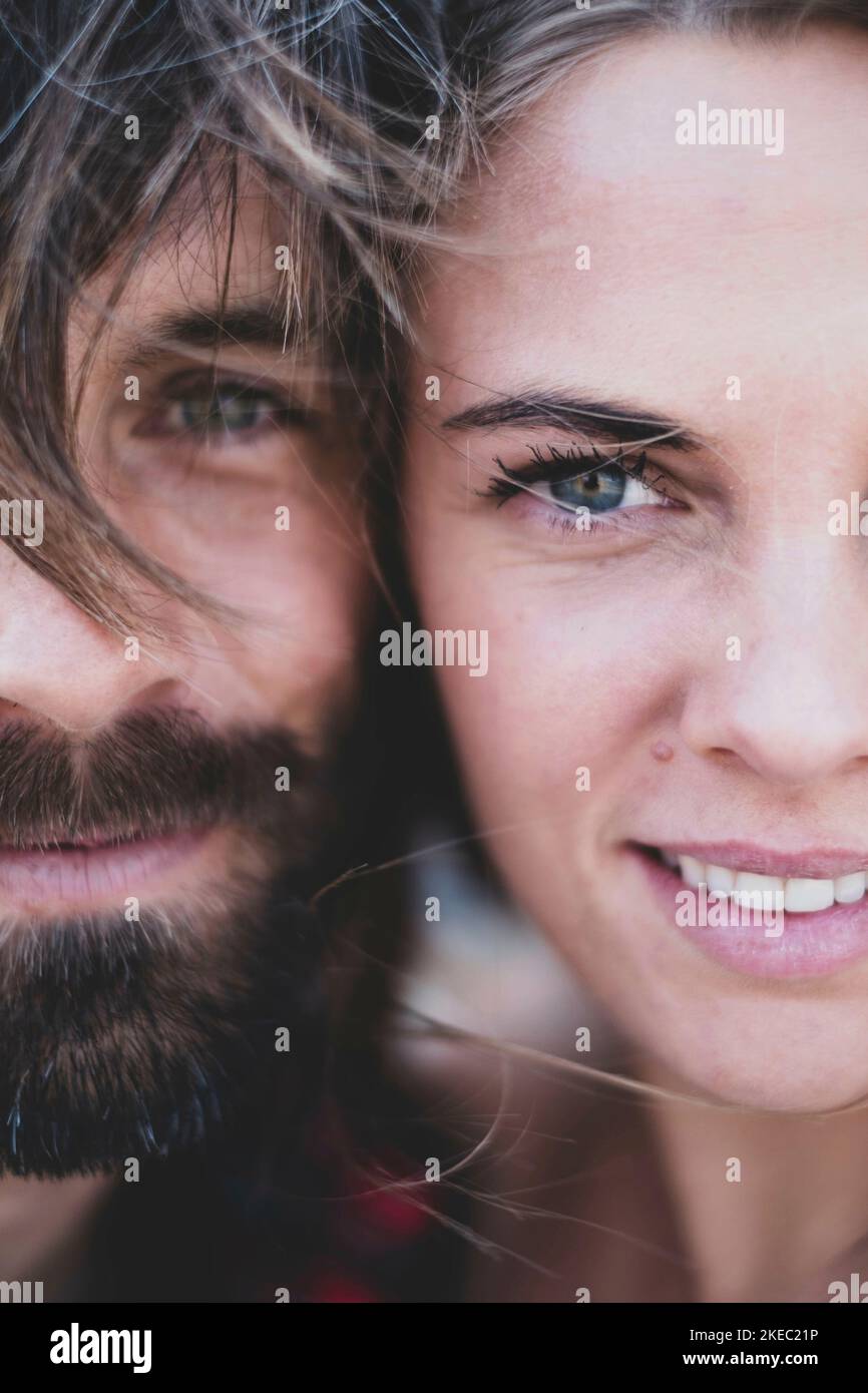 portrait and close up of two bbeautiful and handsome adults smiling and looking at the camera - woman with blue eyes and man with beard and green eyes Stock Photo