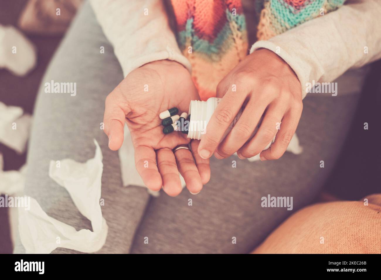 Close up of couple of two hands of woman taking pills and medicaments alone and isolated at home on the sofa. Stock Photo