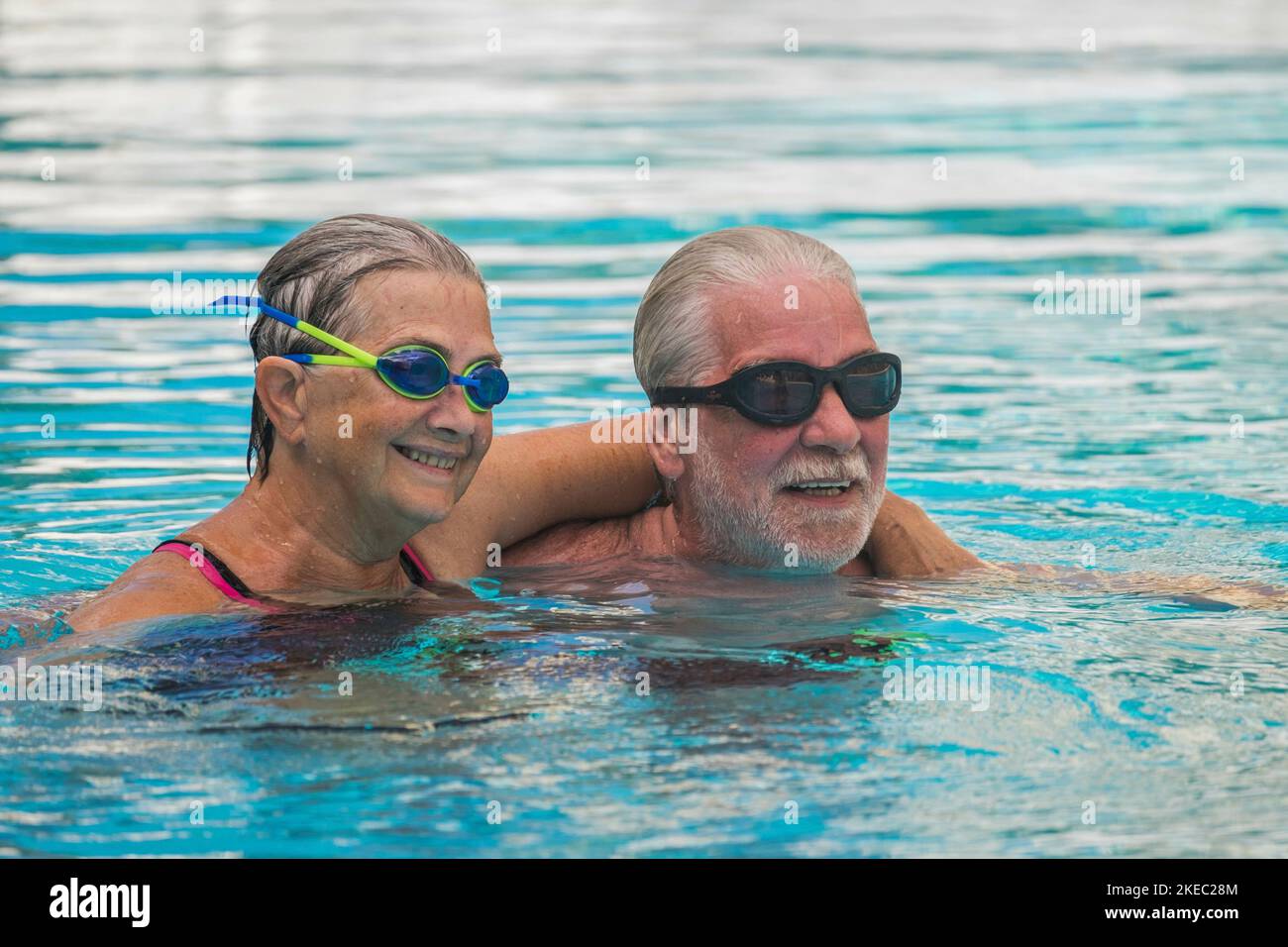 couple of pensioners seniors in the pool swimming and having fun together hugged - healthy and fit concept doing exerise together in the water - active mature people Stock Photo