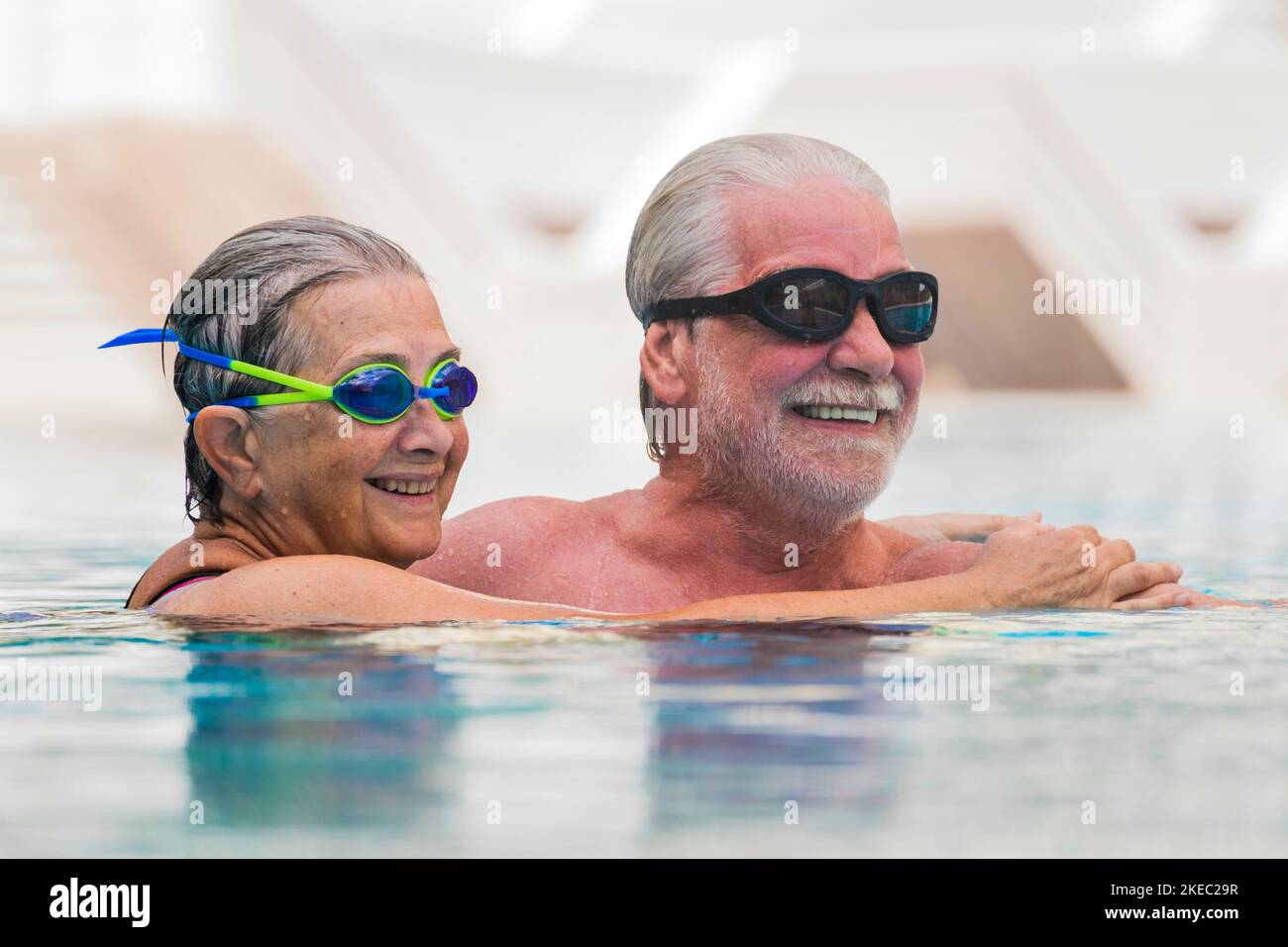 beautiful couple of two seniors together at the swimming pool having fun - woman hugged at her husband smiling with love Stock Photo