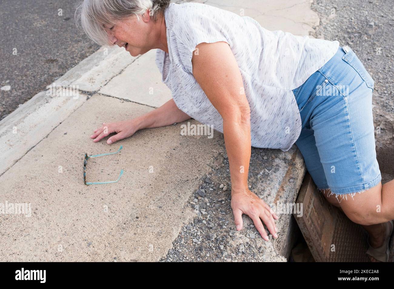 one mature woman fall in a street hole needing help - walking putting the foot inside of the hole - prolematic senior Stock Photo