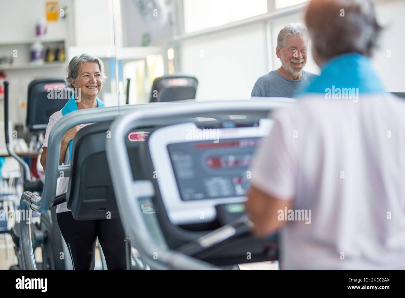 couple of two happy and fitess seniors doing exercise in the gym together running on the tapis roulant - active lifestyle Stock Photo