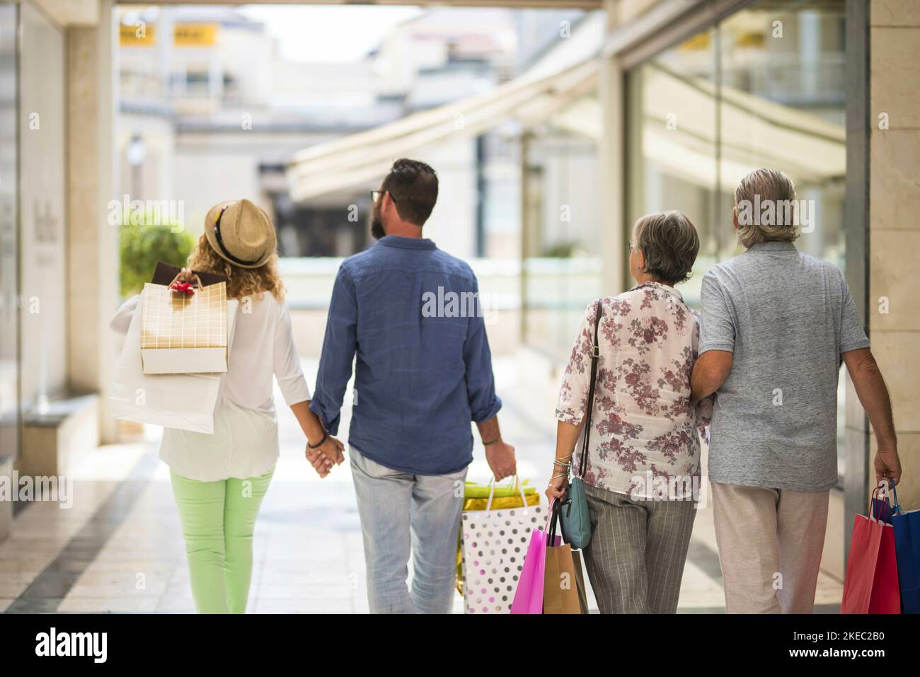 group or family walking together in a mall doing shopping and holding shopping bags - adults and seniors looking at the shops or stores Stock Photo
