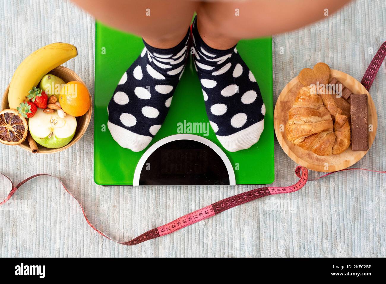close up and portrait of legs and feet weighing on a weight scale to see if she has lose weight after a healthy lifestyle eating fruit Stock Photo