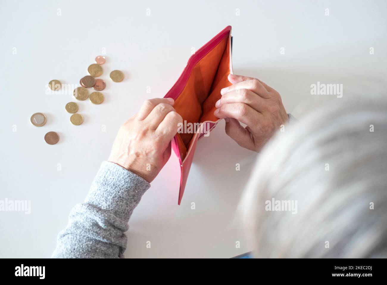 close up of mature woman looking inside of her wallet without any dollar or euro inside it - poor pensioner with difficult to arrive at the and of the month Stock Photo