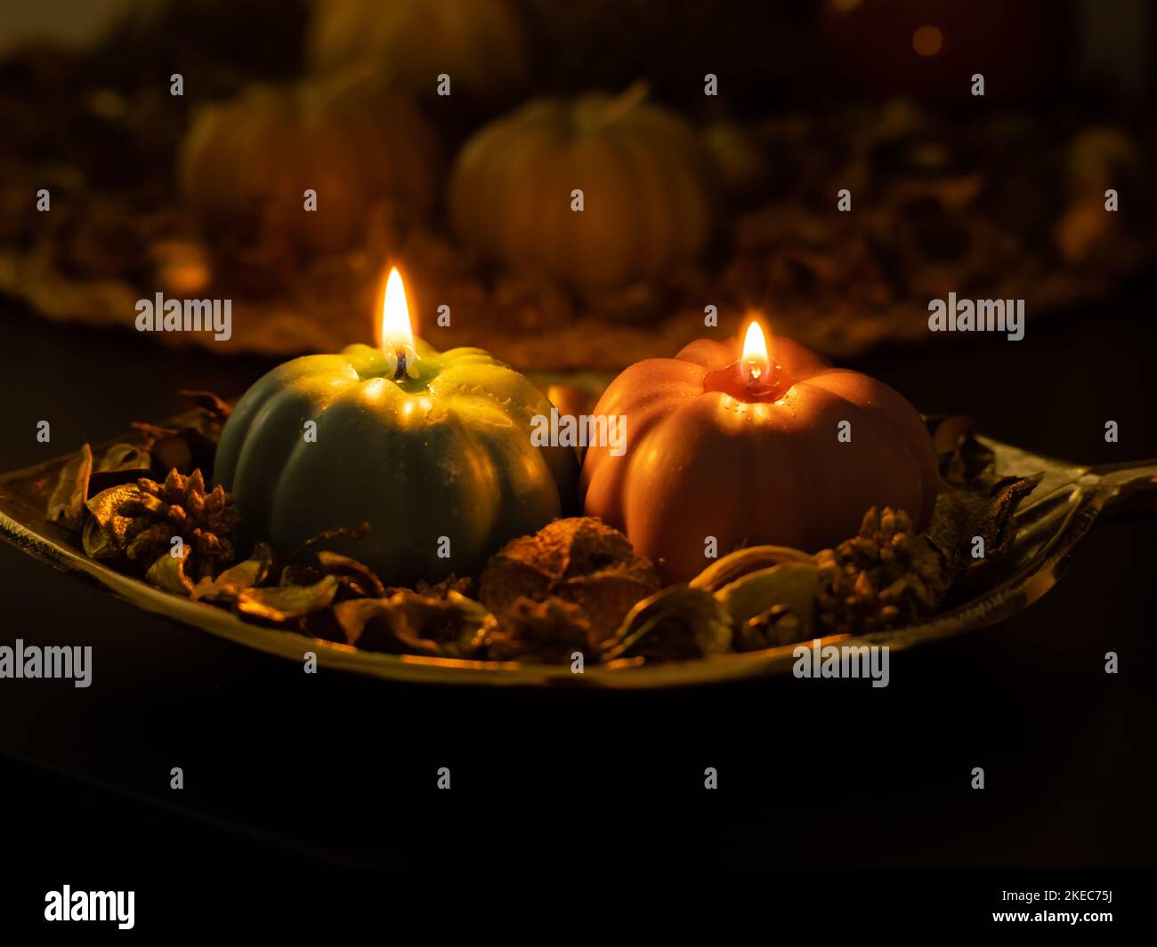 Pumpkin shape candles in a cozy arrangement. Warm light of the glowing soy wax illuminates the decoration. Stylish seasonal objects for the autumn. Stock Photo