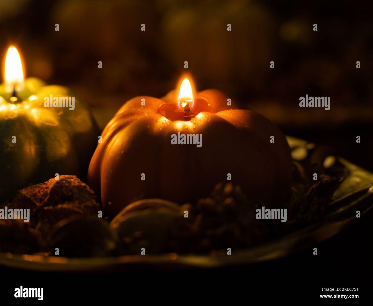 Close-up of a Pumpkin shape candle in a dark setting. Fire is glowing and making a warm atmosphere. Beautiful autumn decoration objects in the room. Stock Photo