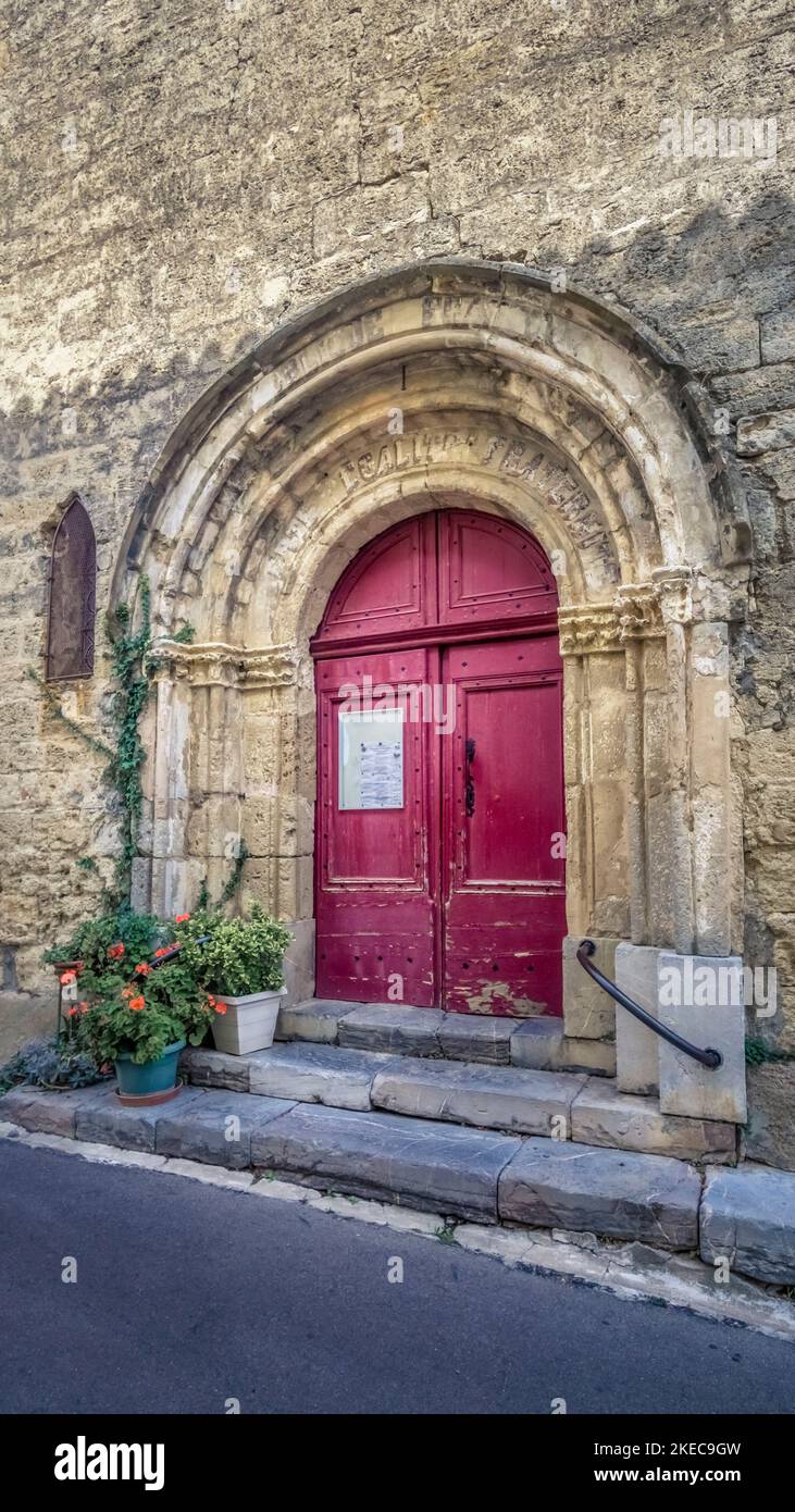 Entrance gate of the church Notre Dame in Moussan. In the portal arch there are still remains of the slogan 'Liberté, Égalité, Fraternité' carved in the time of the French Revolution. Stock Photo