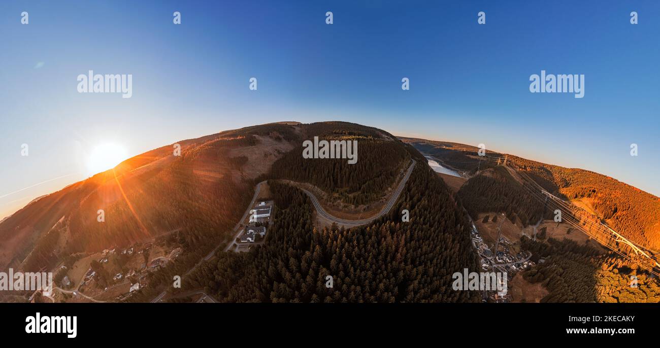 Germany, Thuringia, Goldisthal, village, road, operating building pumped storage power plant, dam, dam wall, forest, mountains, railroad high speed line in background, railroad bridges in background, overview, high voltage lines, sunrise, partly back light, overview, hemisphere panorama Stock Photo