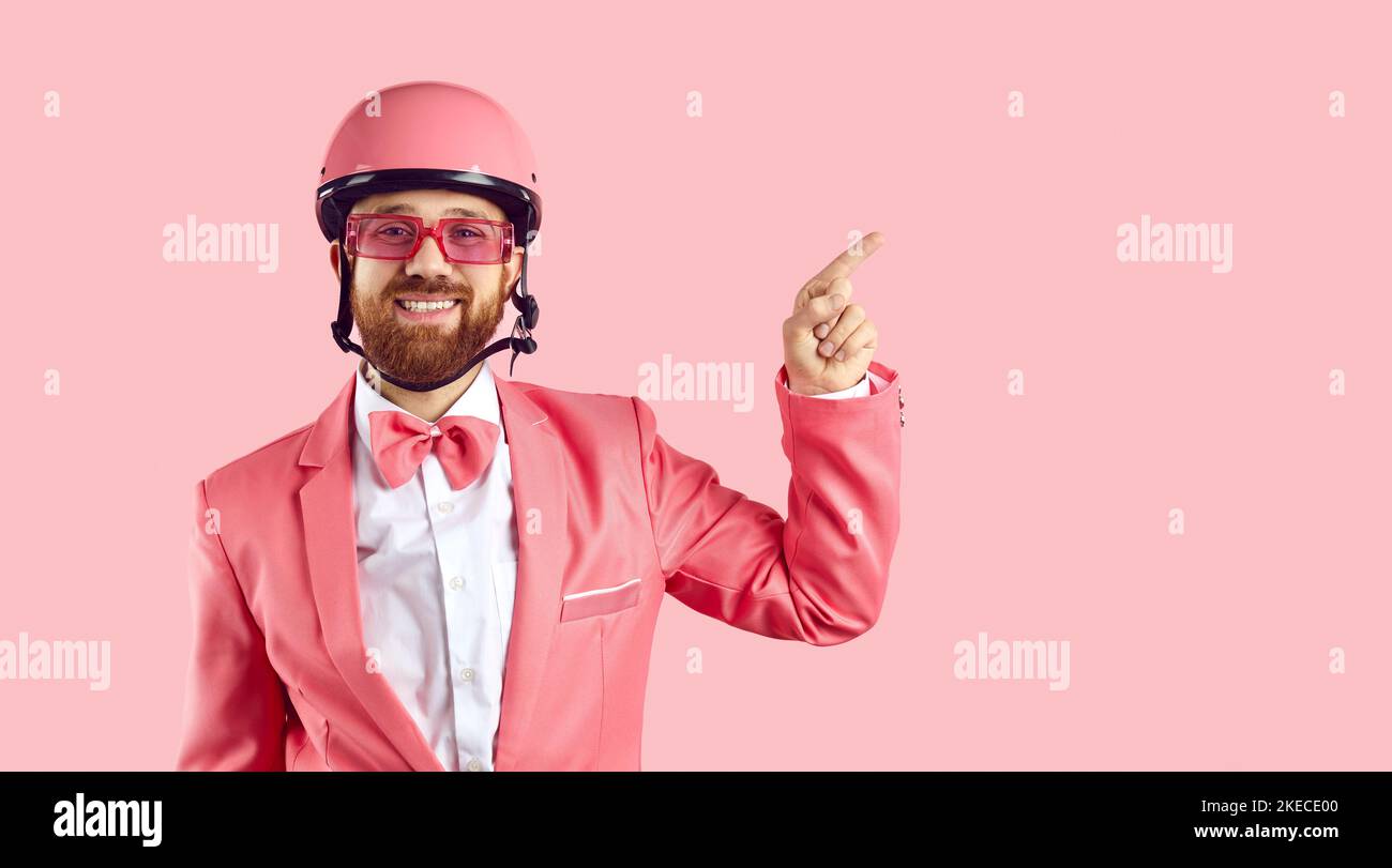 Funny man in pink bike helmet, suit, bow tie and glasses smiling and pointing to side Stock Photo