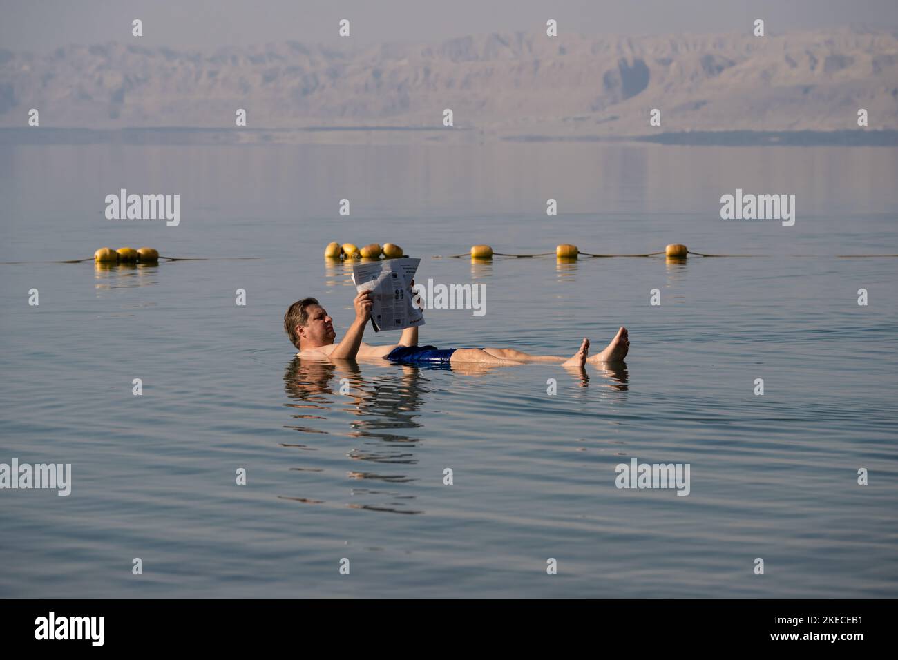 Dead Sea, Jordan - November 1 2022: Reading Newspaper in the Dead Sea in Jordan; a Man Floating and Swimming on his Back in the Salt Water Stock Photo