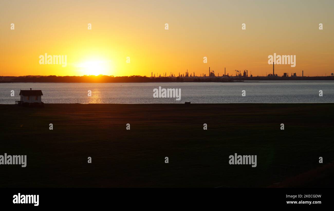 Industrial skyline at sunset, view across Delaware River, from Fort Mott on New Jersey side, Pennsville Township, NJ, USA Stock Photo